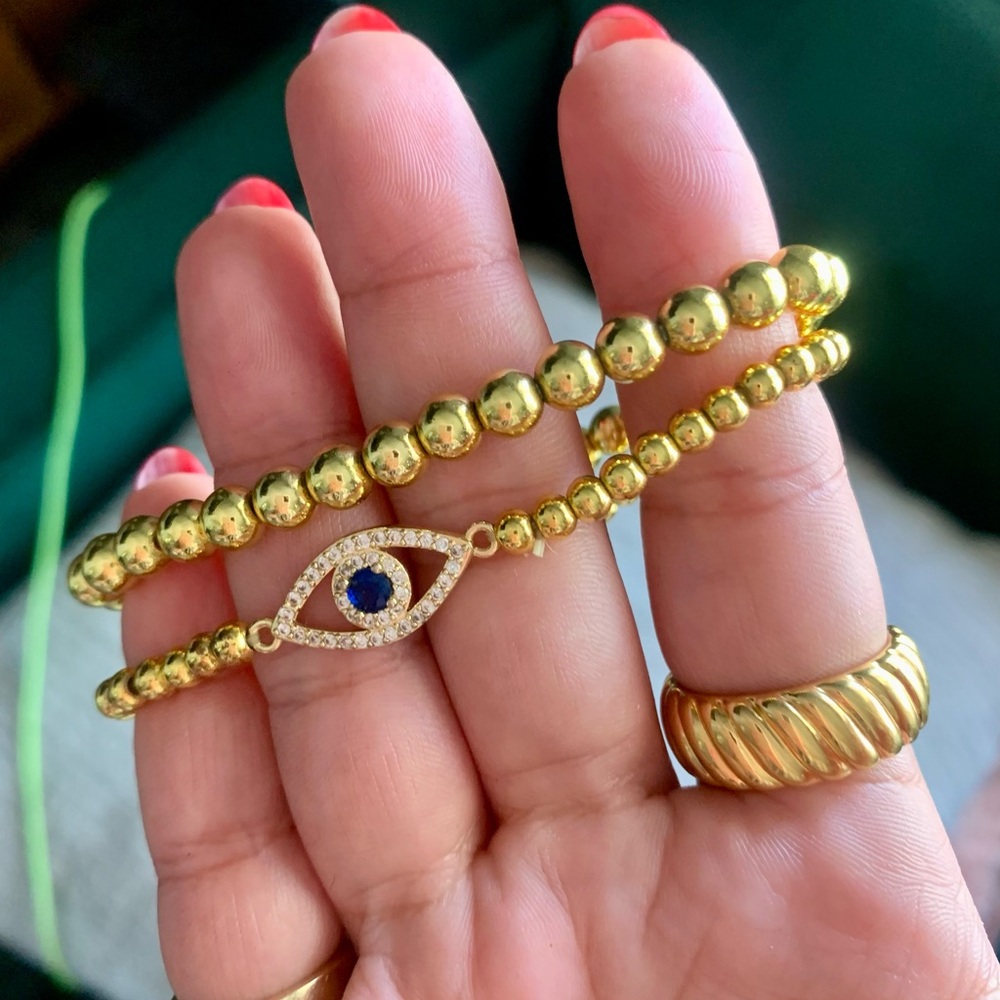 Gold tone bead layering bracelets with evil eye charm